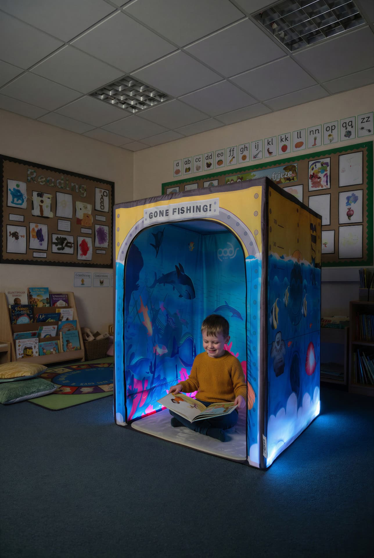 Boy reading inside the Sub Aqua Quest underwater-themed sensory tent in a school reading corner
